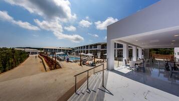 Hotel moderno com área de piscina, espaço para sentar ao ar livre e céu claro.
