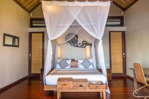 A bedroom with a four-poster bed, wooden headboard, and a woven mat on the floor.
