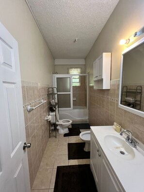 A compact bathroom with a toilet, sink, and bathtub. - The Seclusive Mansion, Copthall (Roseau)