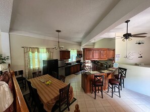 A spacious kitchen with a dining area, wooden cabinets, and a ceiling fan. - The Seclusive Mansion, Copthall (Roseau)