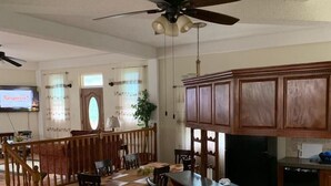 A spacious kitchen with wooden cabinets, a dining area with a wooden table and chairs, and a ceiling fan.