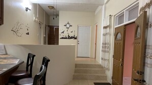 A dining area with a table and chairs, a staircase leading to a door, and a wall with a cityscape decal.