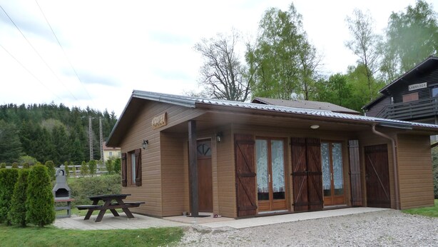 A wooden lodge with a picnic table and a fireplace.