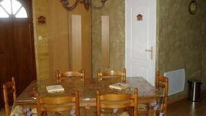 A dining room with a glass table, six wooden chairs, a chandelier, and a white door.