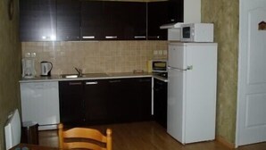 A compact kitchen with dark cabinets, a white refrigerator, a microwave, and a sink.