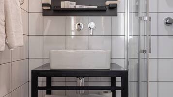 Une salle de bain avec un lavabo blanc, un meuble-lavabo noir et une cabine de douche en verre.