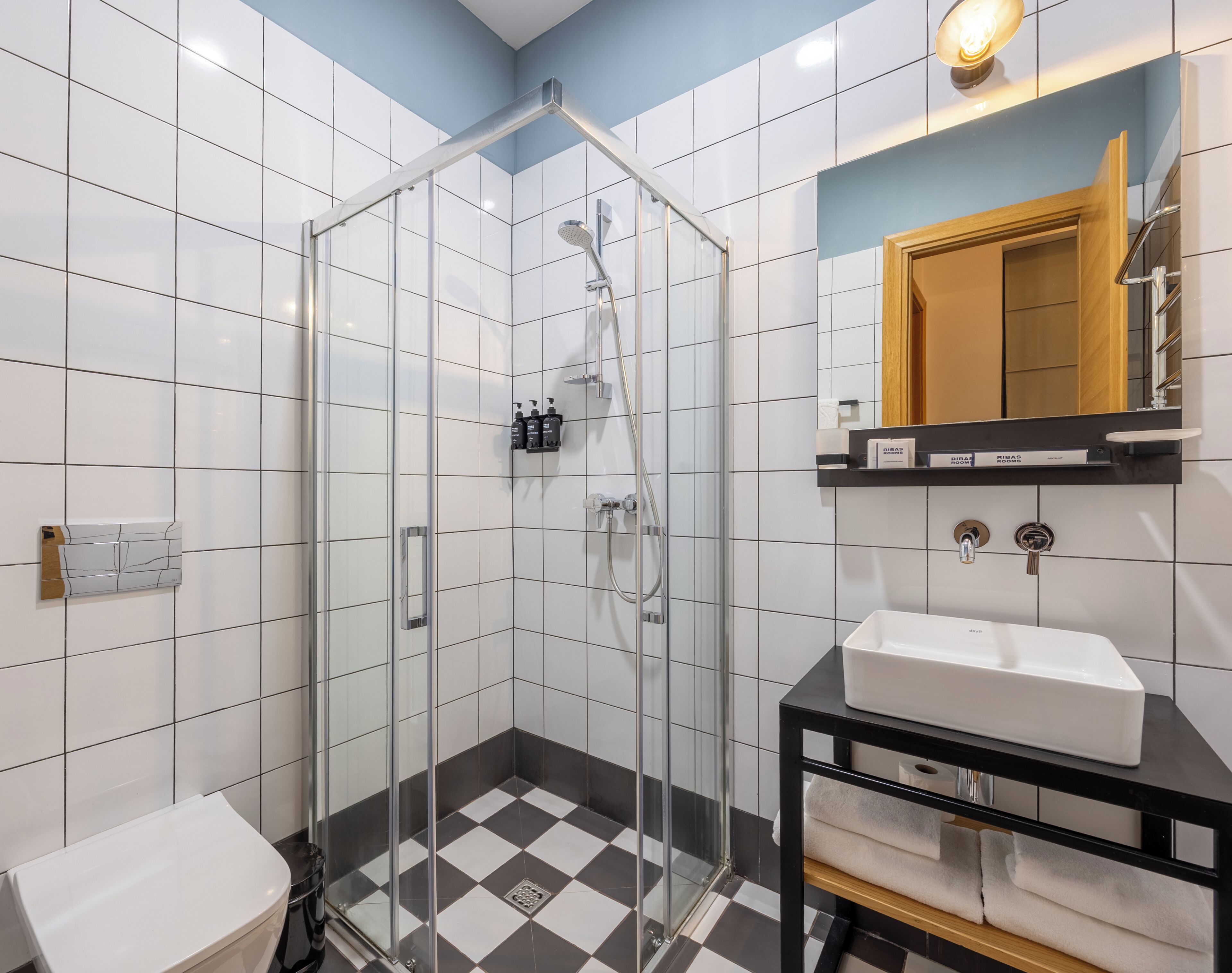 A modern bathroom with a glass-enclosed shower, a white sink, and a black vanity.