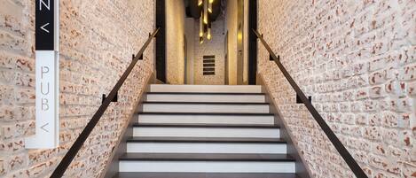 A staircase with a brick wall on either side, leading to a reception area labeled "RECEPTION PUB".