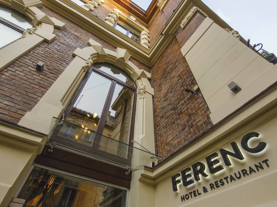 The exterior of Ferenc Hotel & Restaurant with a classic architectural style, featuring a prominent entrance and a glass facade.