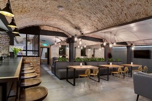 A modern interior with exposed brick walls, a bar area with stools, and seating arrangements. - FERENC Hotel & Restaurant (Lviv)