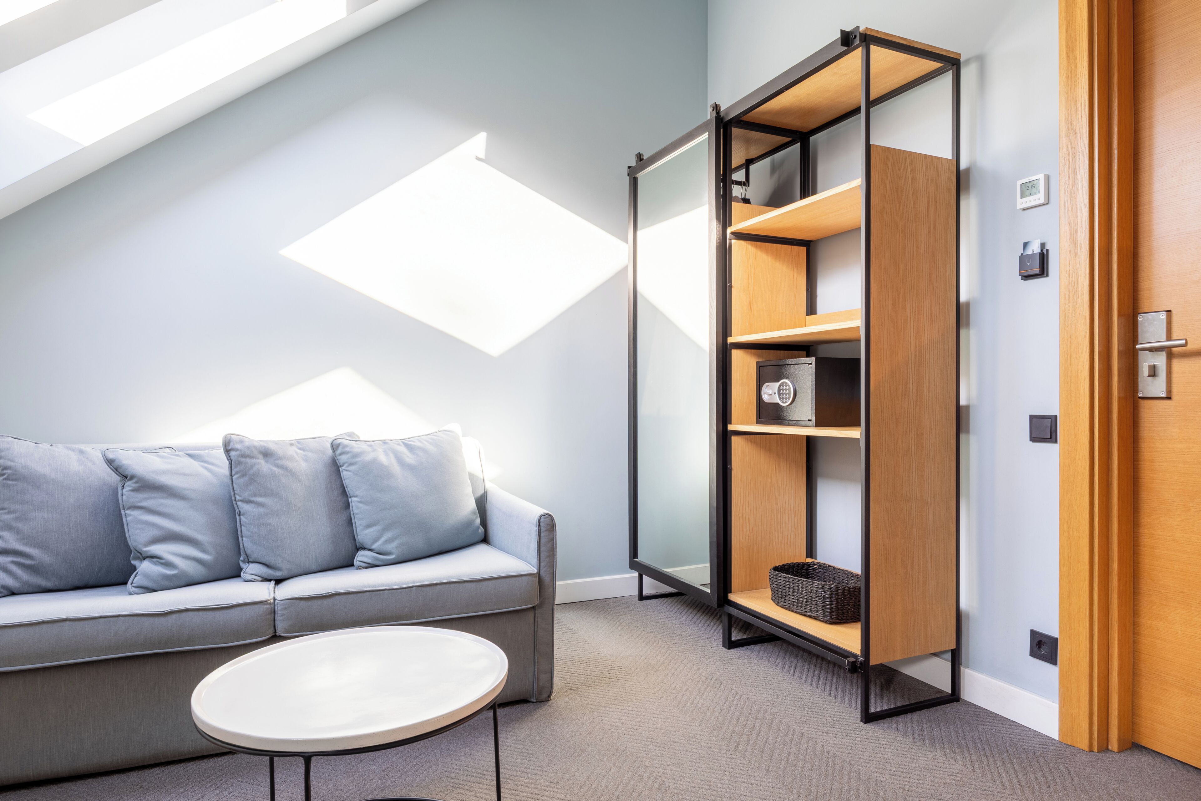A modern room with a sofa, a small table, a bookshelf, and a door.