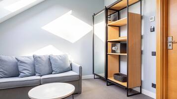 A modern room with a sofa, a small table, a bookshelf, and a door.