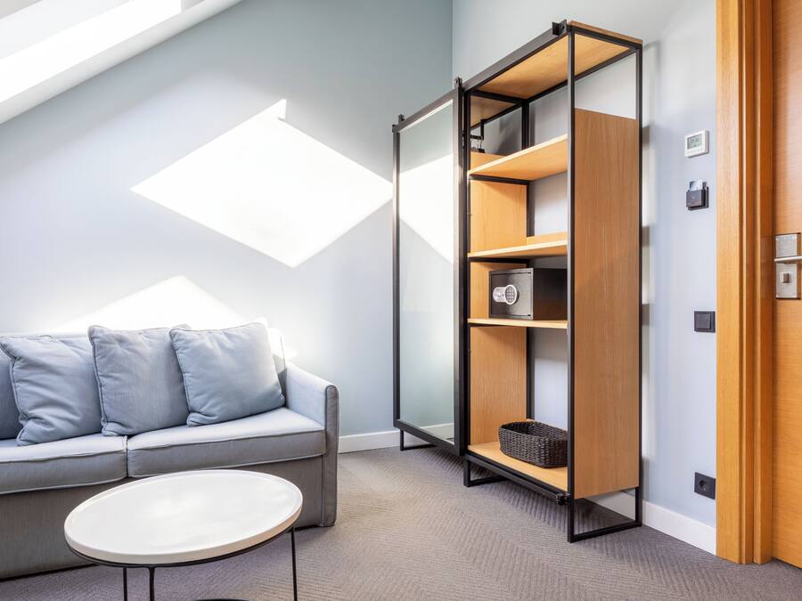 A modern room with a sofa, a small table, a bookshelf, and a door.