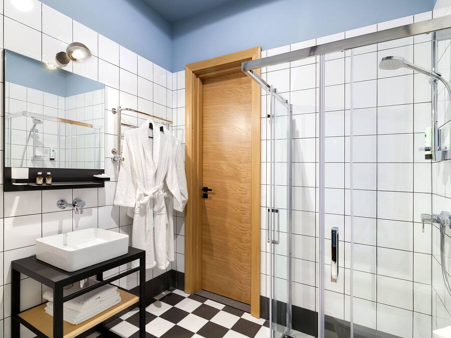 A modern bathroom with a large mirror, white sink, and a glass-enclosed shower.