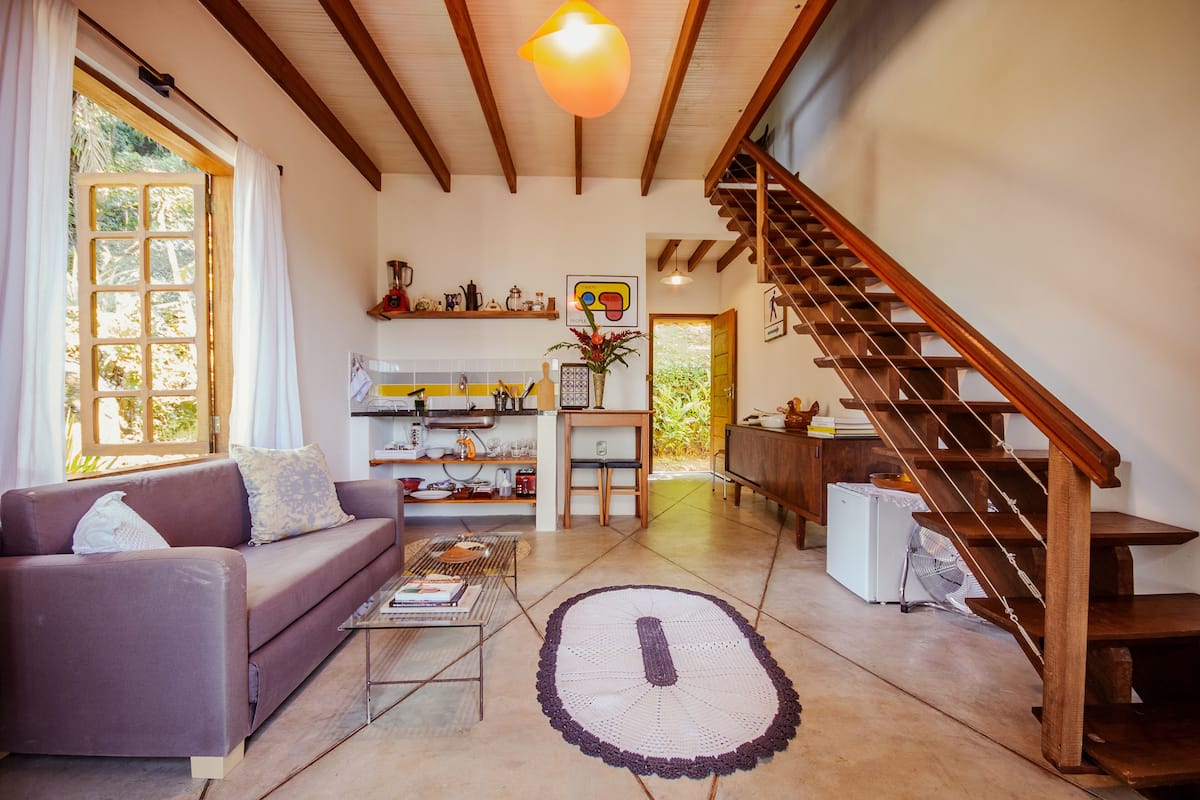 A cozy living room with a sofa, coffee table, and a staircase.