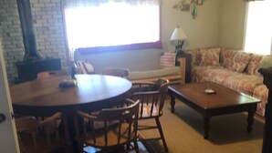 Una sala de estar con una mesa de comedor de madera, sillas, un sofá y una mesa de centro.