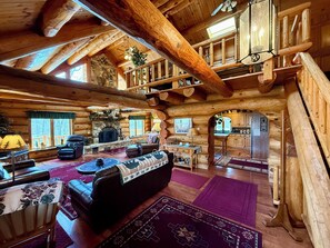 Ein rustikales Blockhaus-Interieur mit Kamin, Ledersitzmöbeln, Essbereich und Küche.