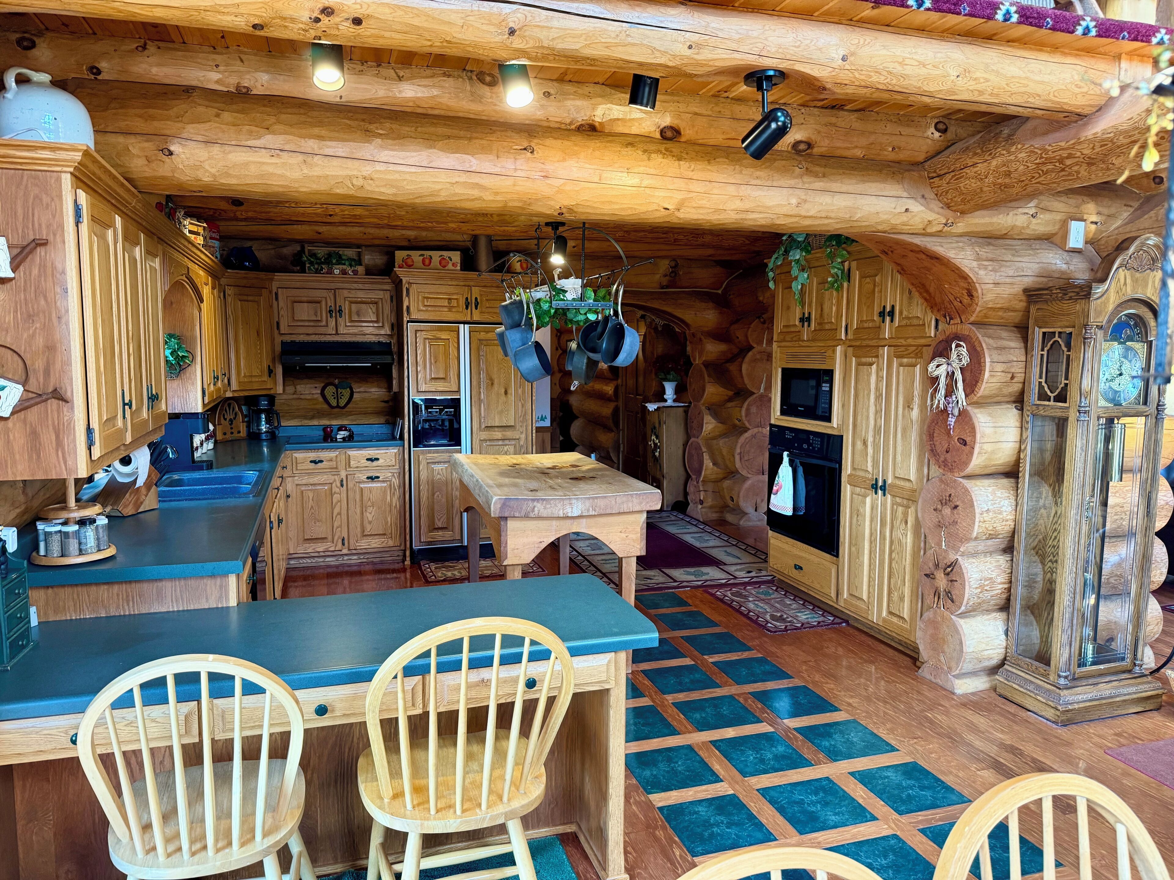 A rustic kitchen with wooden cabinets, a central island, and hanging plants.