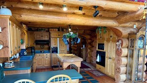Una cocina rústica con armarios de madera, una isla central y plantas colgantes.