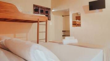 A bunk bed with a wooden ladder, a flat bed with white bedding, a wall-mounted TV, and a mirror reflecting a bed and a window.