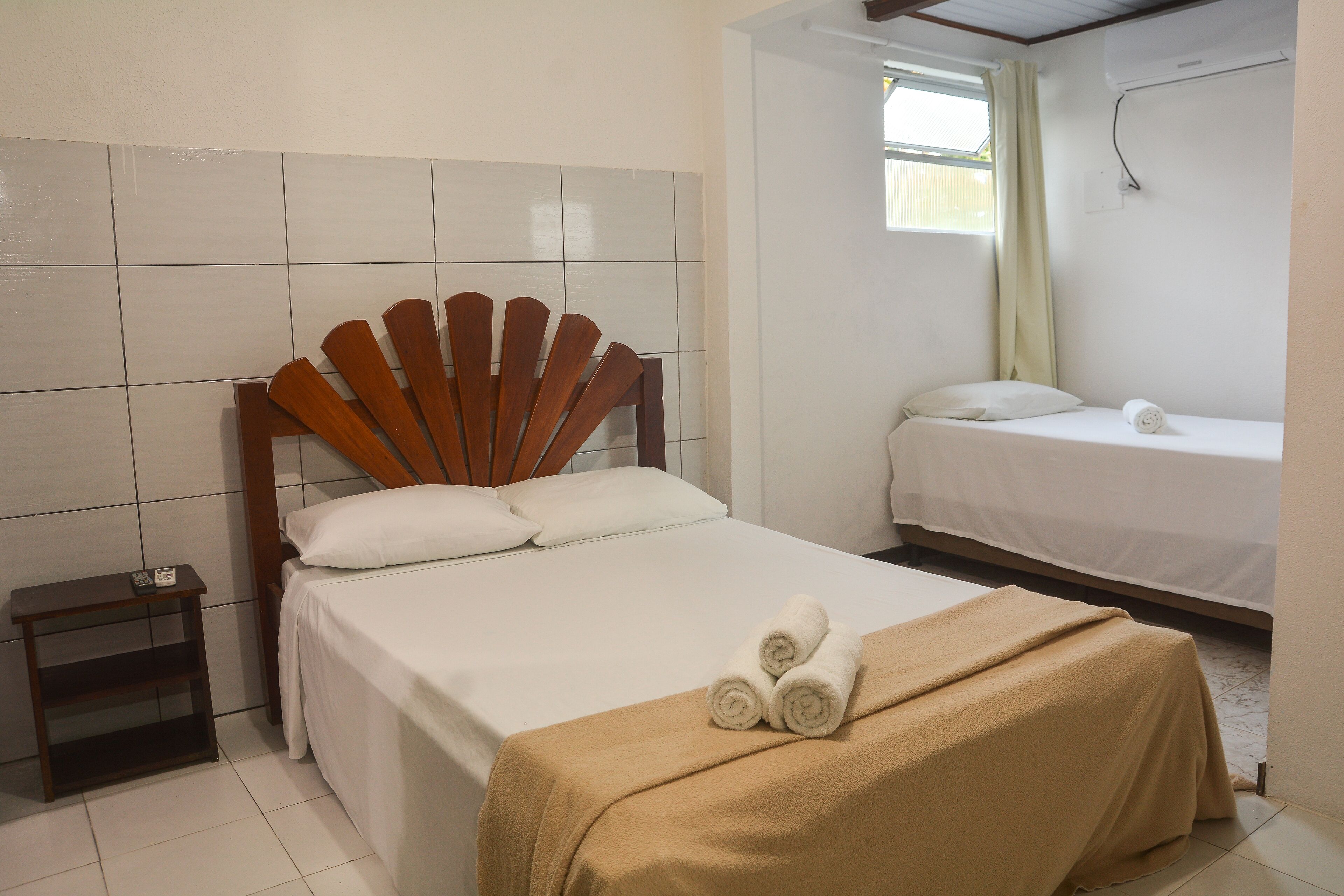 A hotel room with a bed, a nightstand, and a window.