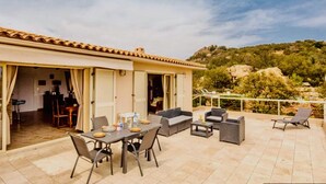 An open-plan living area with a dining table set for four, a sofa, and a balcony with a railing. - Magnificent air-conditioned villa with private pool, 2 bedrooms 2 bathrooms (4 people) (Porto-Vecchio)