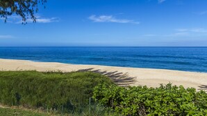A beach with a clear view of the ocean and a sandy shoreline. - Beachfront Cottage at Log Cabins (Haleiwa)