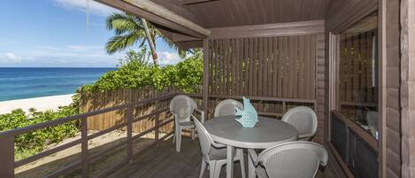 A wooden deck with a table and chairs overlooking a beach.