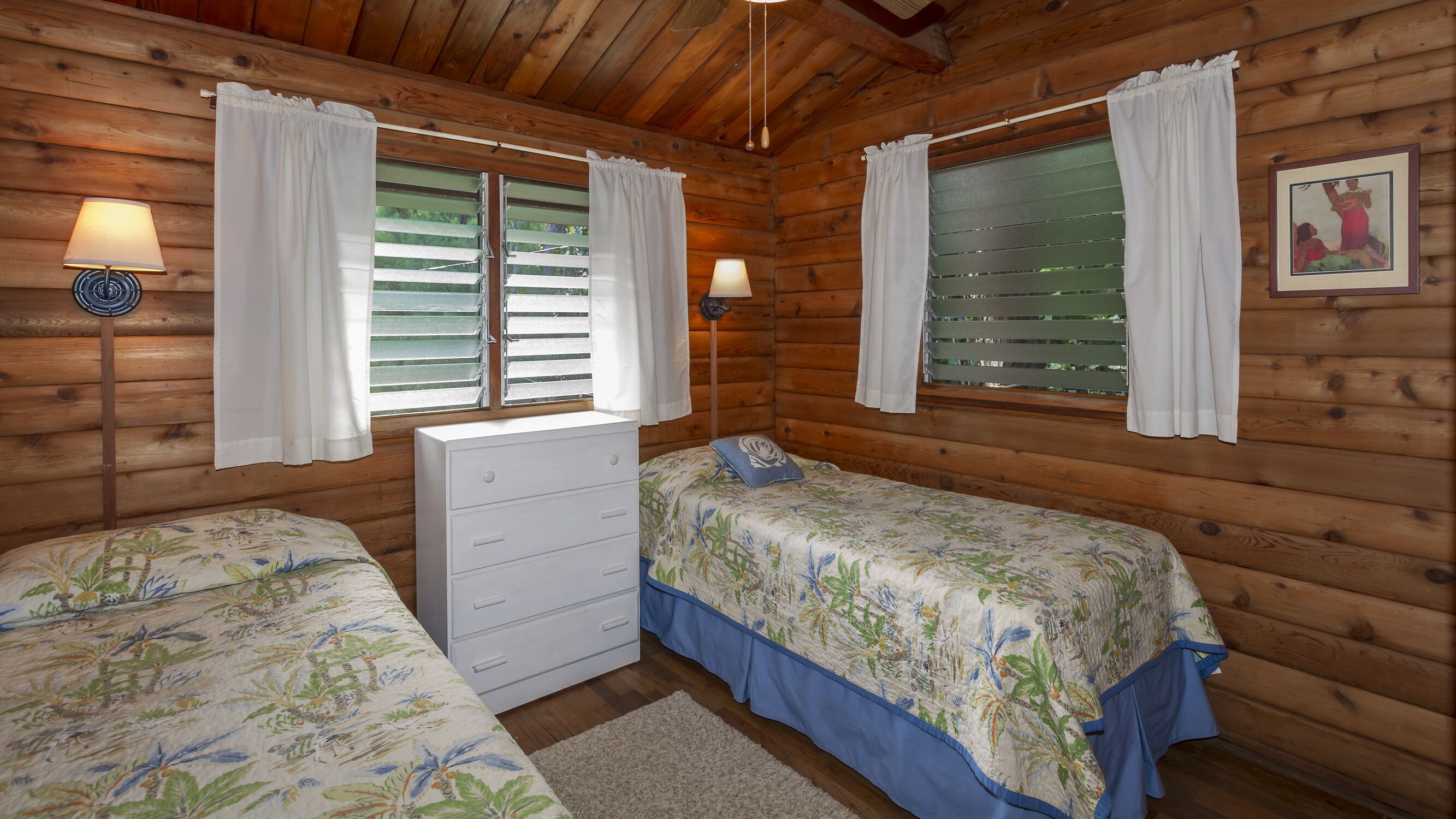 A cabin room with two beds, a dresser, and a window with shutters.
