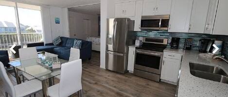 A modern kitchen with white cabinets, stainless steel appliances, and a glass dining table.