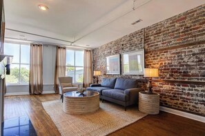 A living room with a brick wall, a sofa, a coffee table, and a lamp.