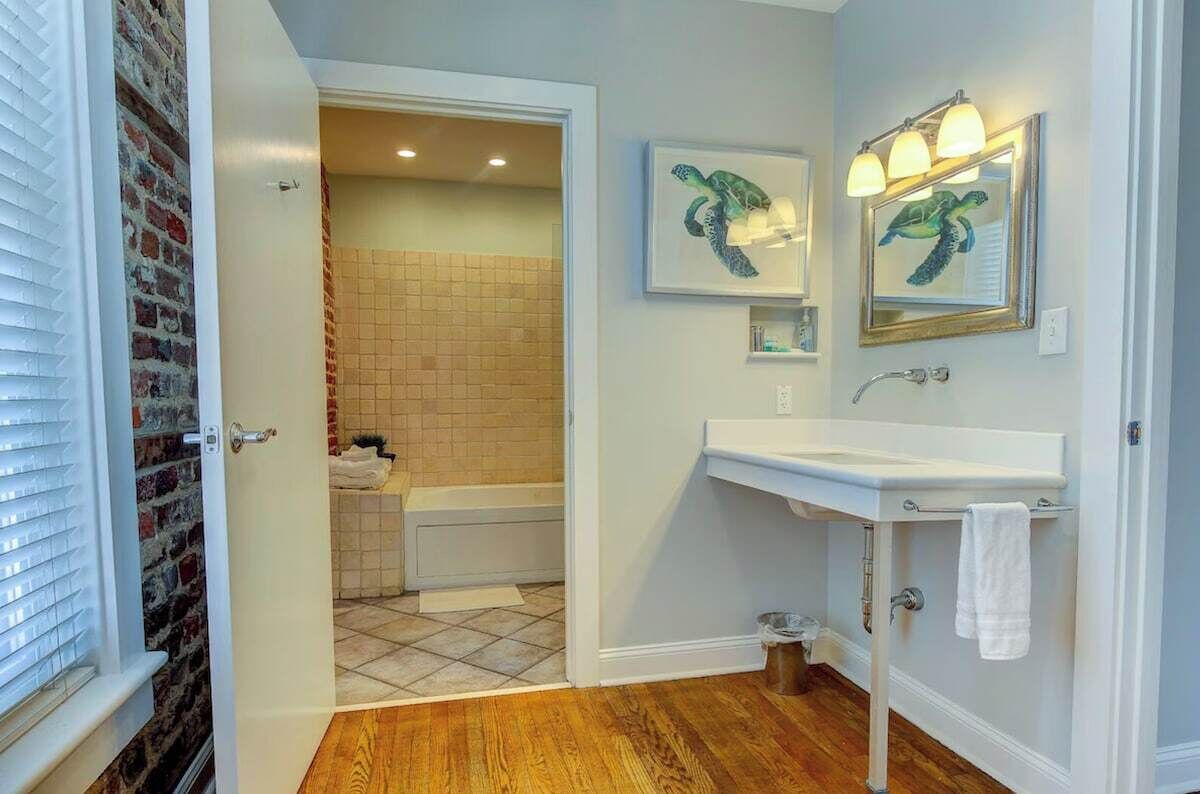 Une salle de bain avec un lavabo blanc, un miroir et deux tableaux représentant des tortues, encadrés.