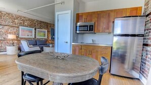 A modern kitchen with a built-in microwave, stainless steel refrigerator, and wooden cabinets. - The Soho Suite - Where Luxury & Location Meet (Charleston)