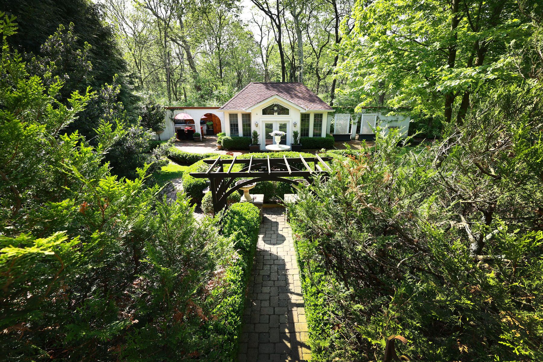 A house with a garden pathway leading to a white building with a red roof.