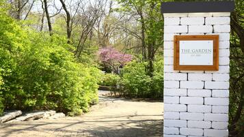 A brick pathway leading to a white wall with a sign that reads "THE GARDEN EST. 2004".