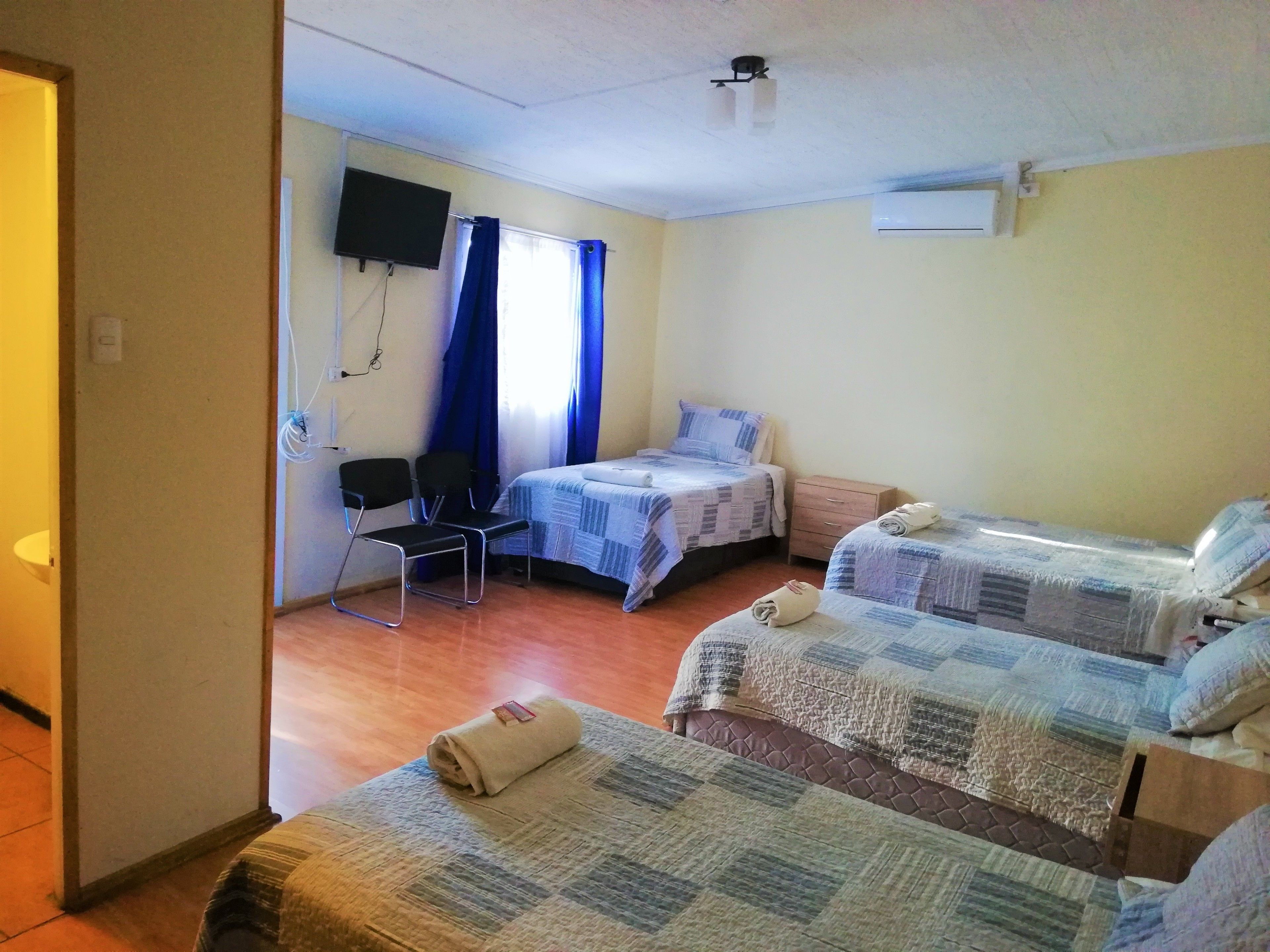 Egy kétágyas szoba, melyben a falra van szerelve egy televízió, van egy szék és egy kis asztal.