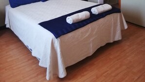 A neatly made bed with blue and white bedding, a wooden headboard, and a blue throw blanket. - Hotel Genova (Los Andes)