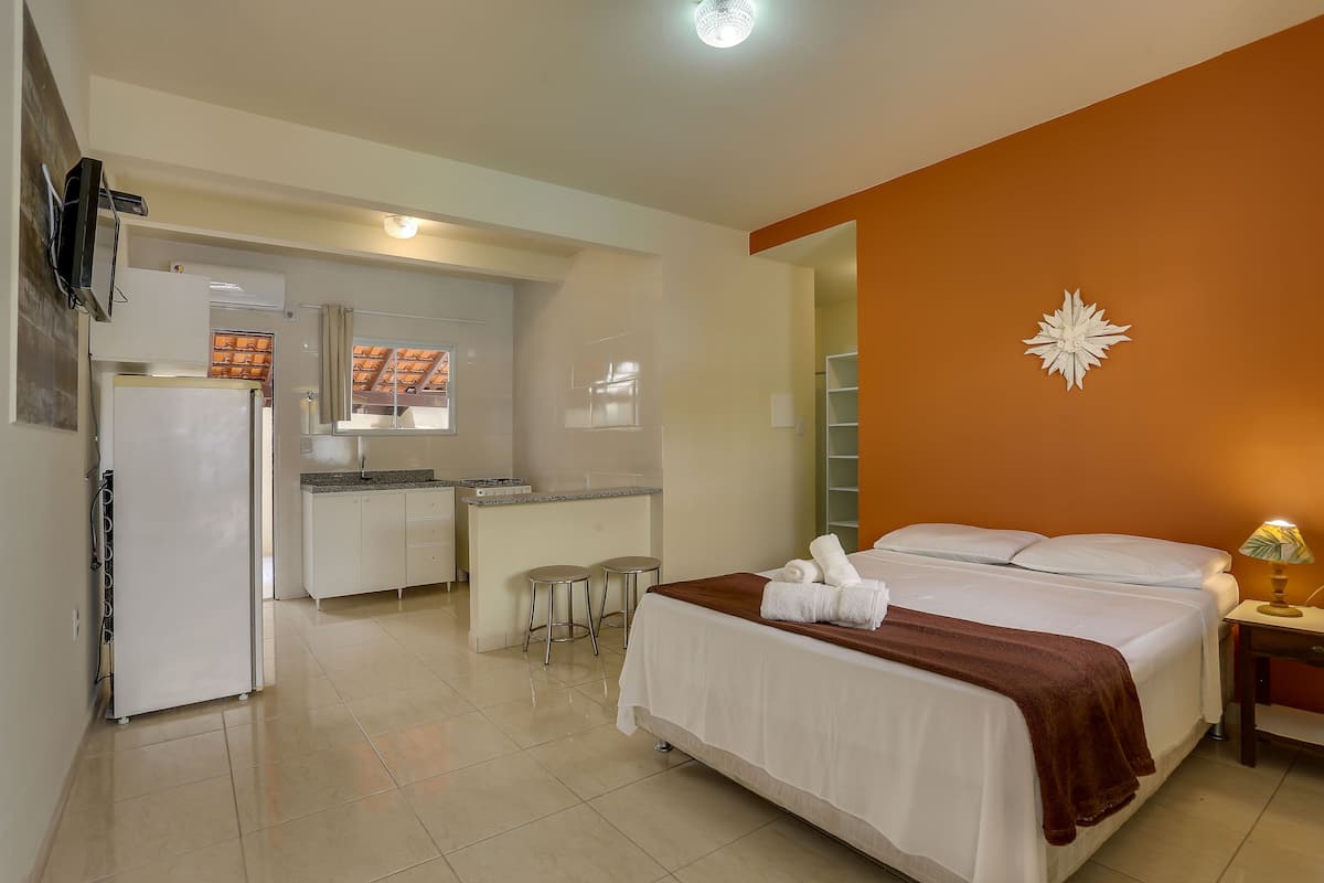 A hotel room with a bed, a desk, a refrigerator, and a kitchenette.