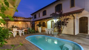 Piscina rodeada por un patio con mobiliario exterior y plantas.