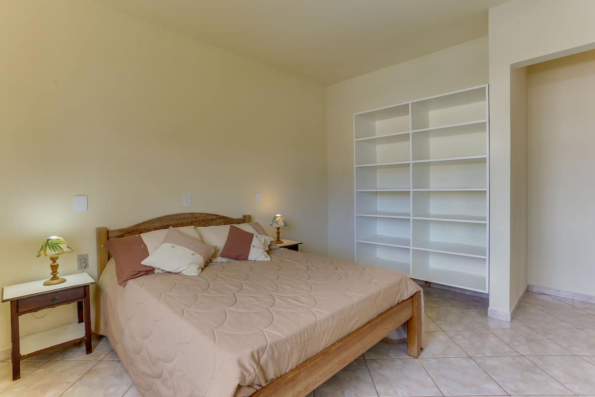 A bedroom with a bed, nightstands, a lamp, and a built-in shelving unit.