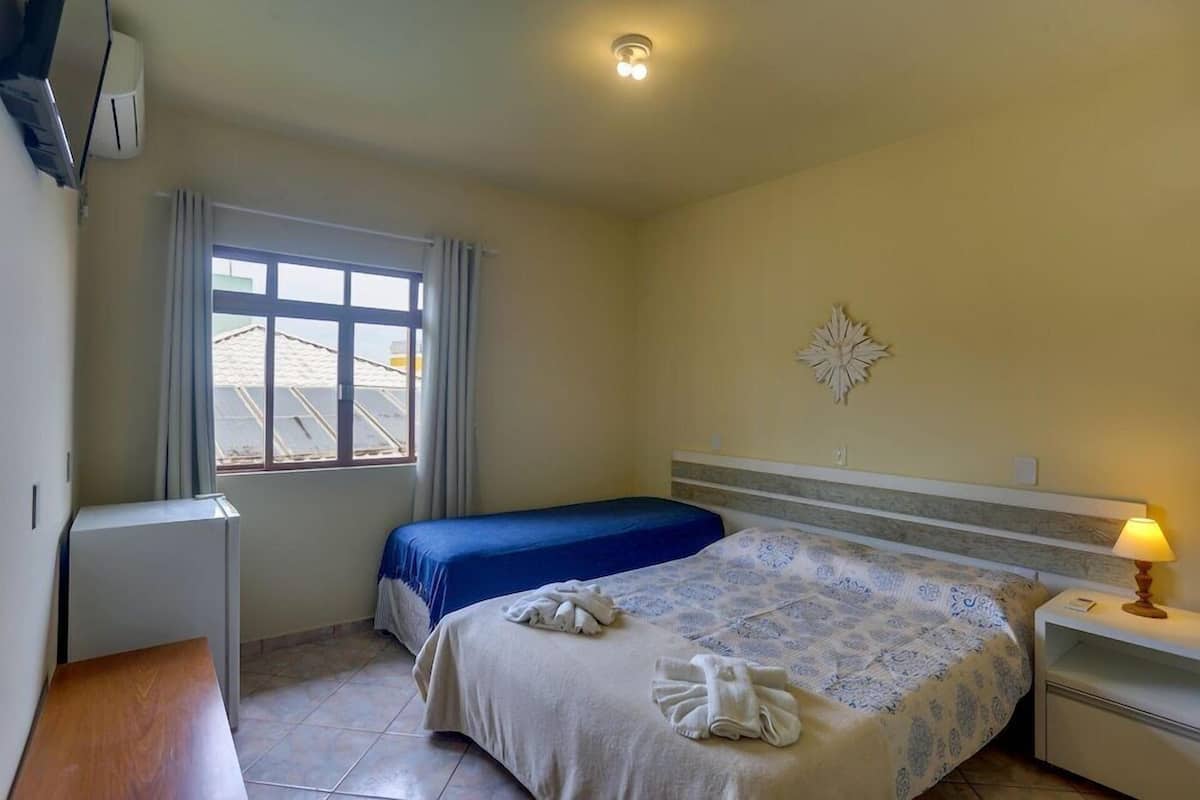 A bedroom with a bed, a desk, a window, and a wall-mounted decoration.