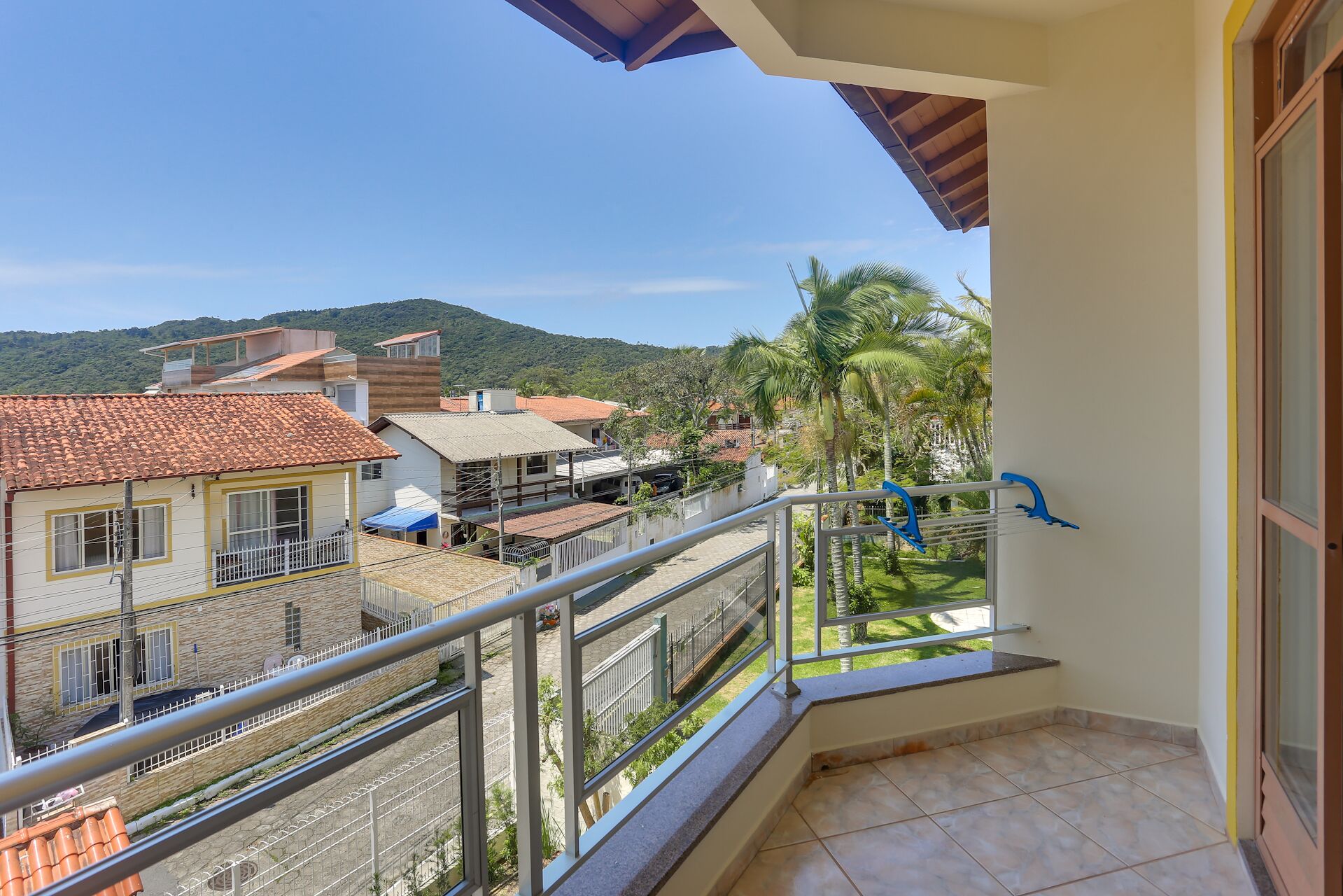 A balcony with a view of a residential area, including houses and palm trees.