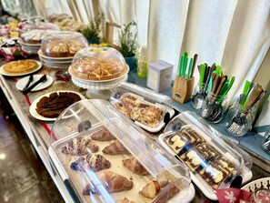 A buffet table with various baked goods and pastries, including croissants and cakes, displayed in clear containers. - Hotel Giacosa (Milan)
