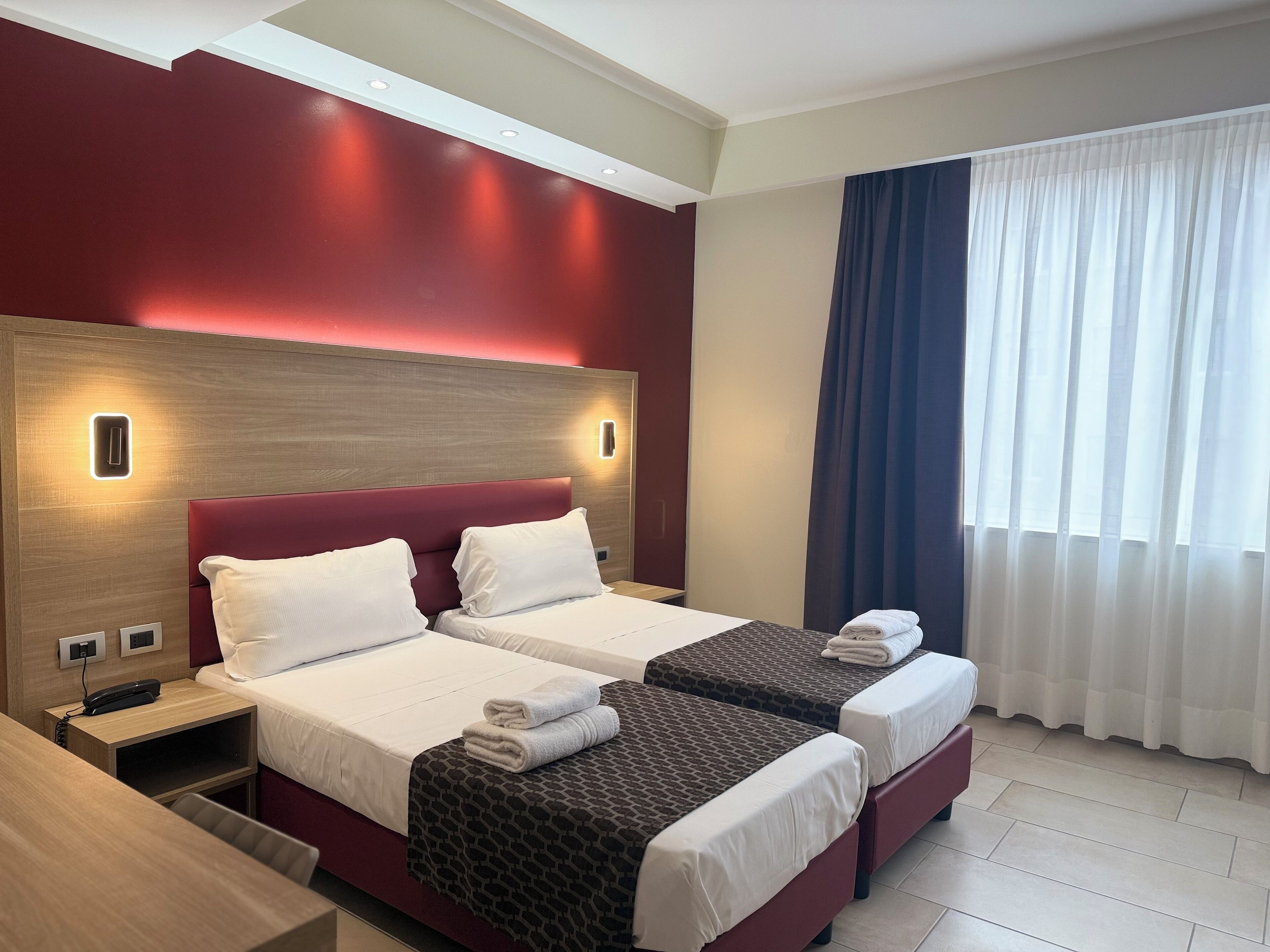 A hotel room with two beds, a desk, and a telephone.