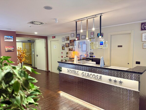 A hotel reception desk with a sign reading "HOTEL GIACOSA," a digital clock, and a "PRIVATE" sign on the wall. - Hotel Giacosa (Milan)