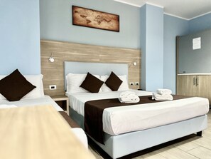 A hotel room with two beds, a wooden headboard, a painting on the wall, and a small table with towels. - Hotel Giacosa (Milan)