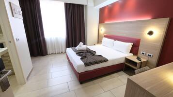 Una habitación de hotel con una cama, una mesita de noche y un escritorio.