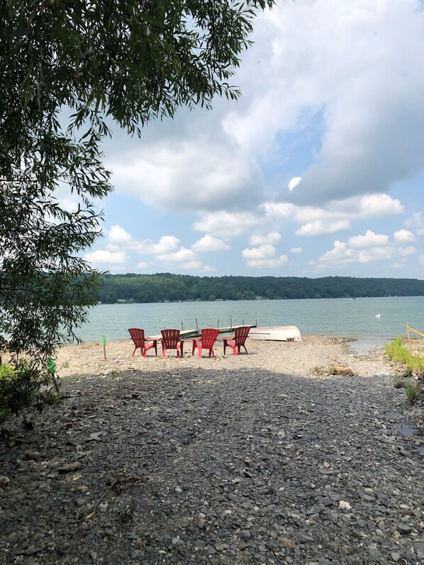 Ein felsiger Strand mit roten Stühlen und einem kleinen weißen Gebäude.