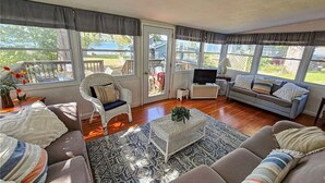 Een gezellige woonkamer met een bank, fauteuil en een televisie op een dressoir.