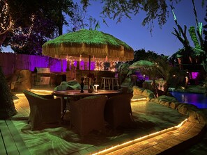 An outdoor patio area with a thatched-roof table and chairs, a grill, and a pool. - The Enchanted Manor- A Magical Hidden Oasis- Paradise!! (Valley Village)